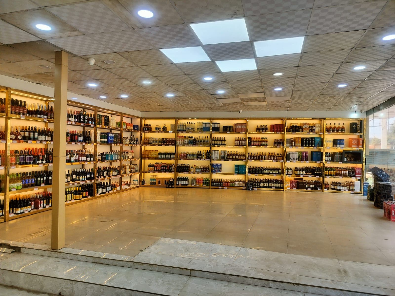 Whisky, rum, vodka and wine bottles displayed on shelves inside a liquor store in Dharam Colony